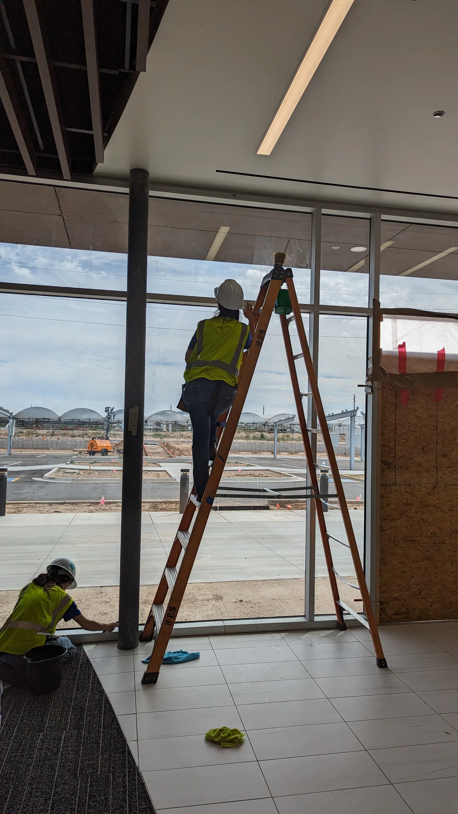 LeBlanc Cleaning technician on a ladder washing windows during post-construction cleanup in Mesa, AZ