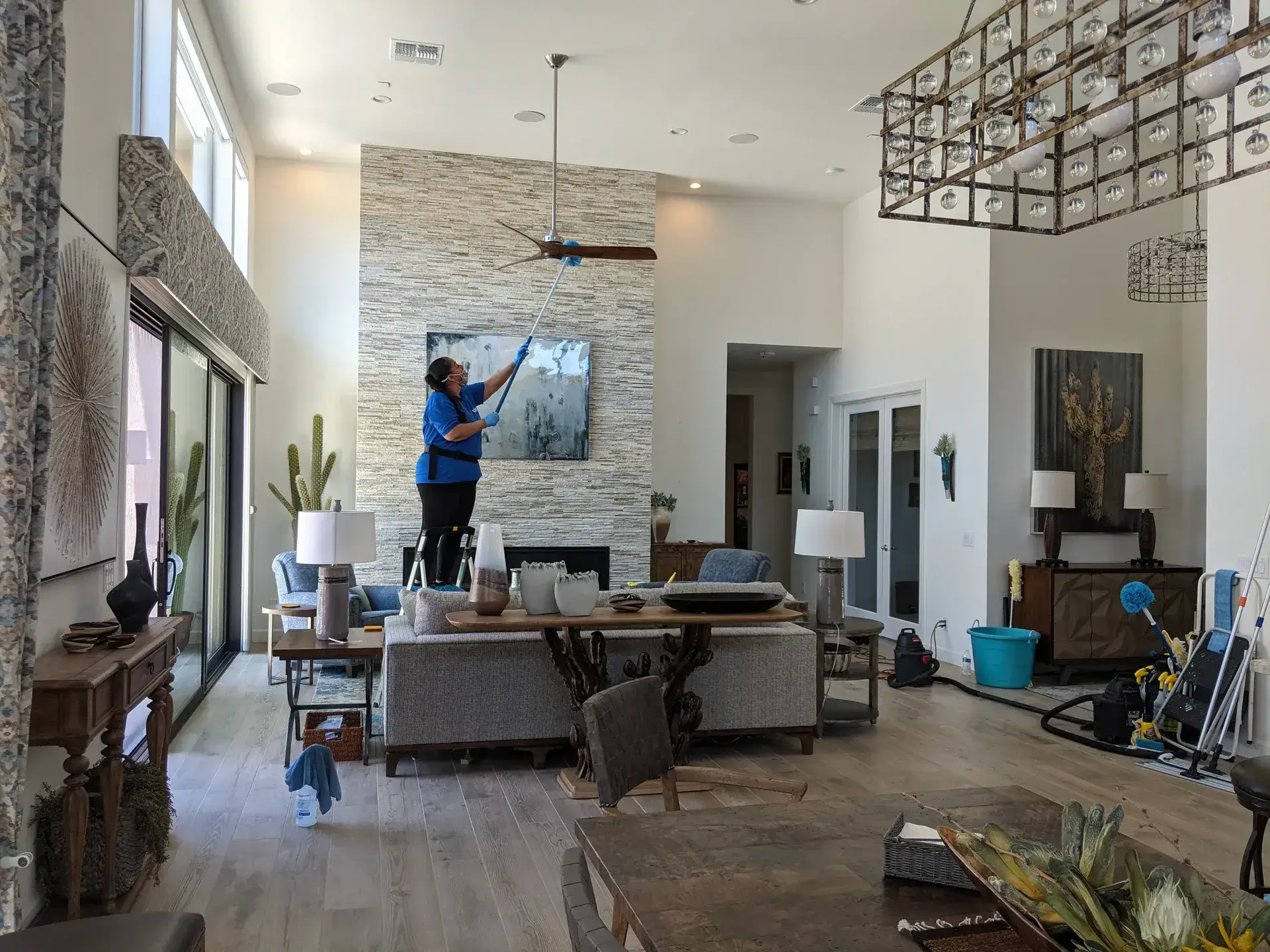 LeBlanc Cleaning team member cleaning a luxury Arizona home with high ceilings and stone fireplace